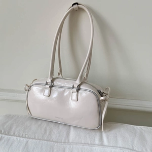 Close-up of cream faux leather underarm bag with zipper closure and brand logo