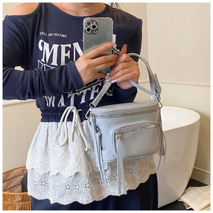 Détail du sac seau bleu clair avec de longs glands en cuir sur les fermetures éclair