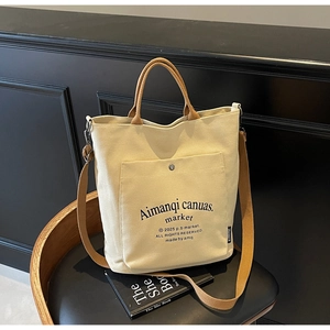 Close-up of cream canvas tote bag with brown straps showing texture and front pocket
