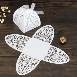 Detailed laser-cut wedding favor box with ribbon on wood background showing flat and assembled state