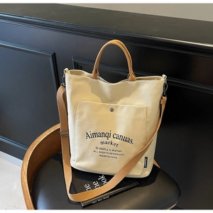 Detail of canvas tote bag showing front pocket with metal snap and logo text