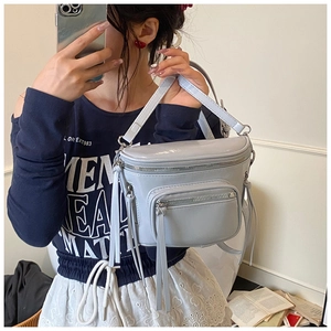 Détail du sac seau brillant bleu clair montrant plusieurs zips et décors de pompons