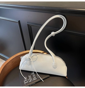 Detailed macro view of cream leather shell bag with delicate side bow and silver zipper