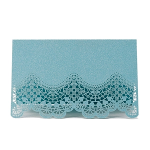 Macro detail of laser-cut lace edge on glittery blue wedding name place cards