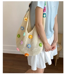 Detail shot of a large knit tote bag with colorful 3D crochet flowers on a cream shoulder bag