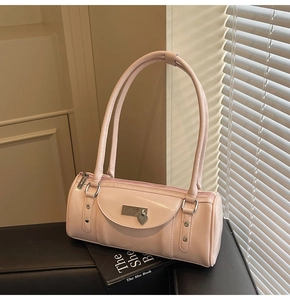 Detail shot of a pink cylinder handbag with heart charm on a book with soft lighting