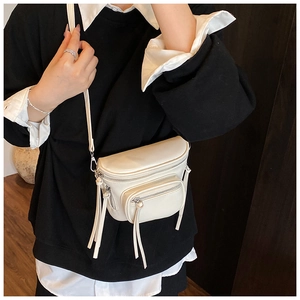 Détail du sac seau en similicuir blanc crème avec pompons et bandoulière réglable