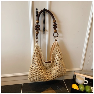 Detail of woven straw tote bag featuring decorative wooden beads and rustic rope handles