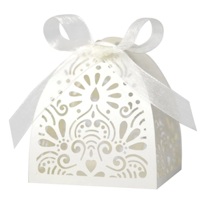 Close-up of white laser-cut wedding candy box with intricate heart pattern and satin bow