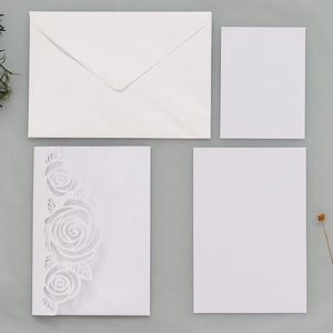 Detail of laser-cut rose pattern invitation with blank inserts and a white envelope
