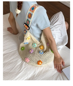 Detail of hand-crocheted shoulder bag with colorful 3D floral appliques and wide straps