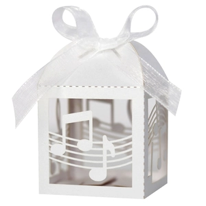 Close-up of laser-cut musical notes and stave on white paper candy box with ribbon bow
