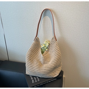 Macro shot of beige crochet tote bag with hollow knit design and brown leather strap