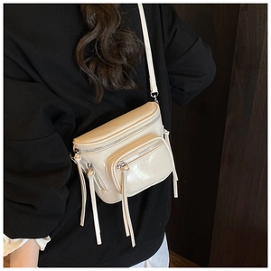 Détail d'un sac seau en cuir beige avec trois fermetures éclair et longs tirettes