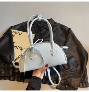 Detail of light blue crescent shell bag with bow decoration and lychee leather texture