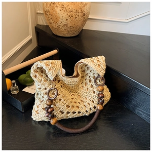Detail of woven straw tote bag with brown wooden beads and bohemian crochet pattern
