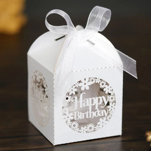 Macro detail of white laser-cut Happy Birthday candy box with elegant ribbon bow