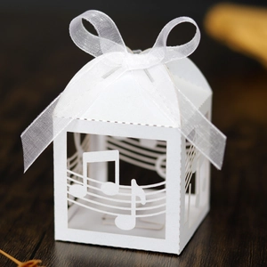 Close-up of laser-cut musical note patterns and white organza bow on paper candy box