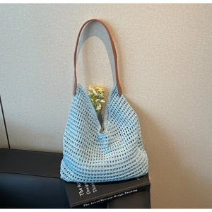 Detailed close-up of light blue hollow crochet tote bag with brown leather strap