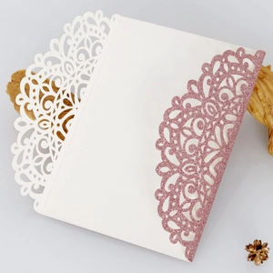 Detail of laser-cut lace pattern on white pearlescent and pink glitter wedding invitation