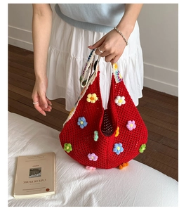 Detail of red hollow knit tote bag featuring colorful 3D crochet floral embellishments