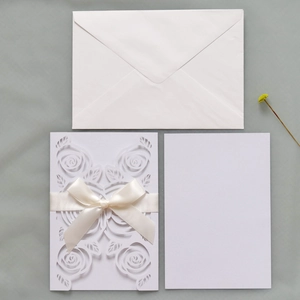 Detail of laser-cut rose hollow invitation with pearlescent finish and silk ribbon