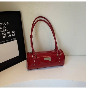 Detail of red patent leather cylinder bag with heart pendant and metallic plate