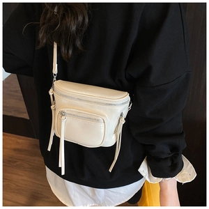 Vue détaillée du sac besace crème avec plusieurs compartiments zippés et des tirettes à franges