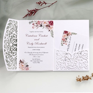 Flat lay of laser cut wedding invitation with floral cards and delicate white paper pocket