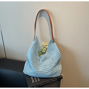 Close-up of light blue hollow knit tote bag with brown leather strap and rivet detail