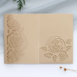 Macro detail of laser-cut rose patterns on elegant champagne gold wedding invitations