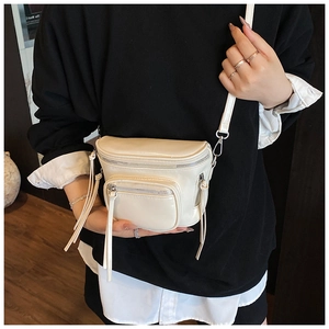 Gros plan d'un sac seau blanc brillant avec ferrures argentées porté par un mannequin