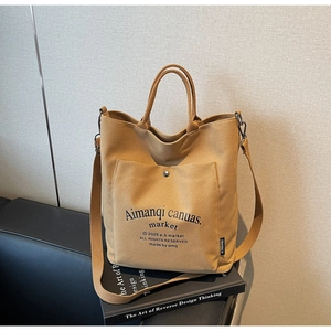 Detail of tan canvas tote bag front pocket with snap button and printed typography