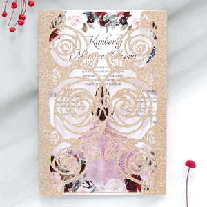 Close-up of laser-cut glitter gold wedding invitation with elegant rose pattern detail