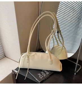 Chic cream leather baguette bag featuring elegant bow detail on a decorative mirror