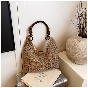 Detail of woven straw tote bag featuring decorative wooden beads and hollow out texture