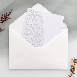 Detailed laser-cut vine patterns on white wedding invitation card with envelope