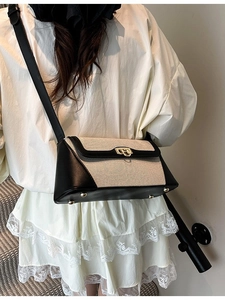 Elegant contrast shoulder bag in beige canvas and black leather worn by a model