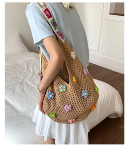 Detail view of large knit tote bag with 3D crochet flowers and embroidered strap