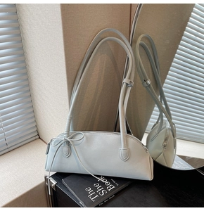 Detail of light blue shell bag with leather bow and metal zipper on mirror