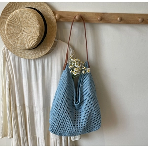 Close-up of light blue crochet knit tote bag with mesh hollow design and brown strap