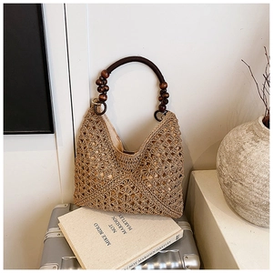 Close-up of hand-woven straw tote bag with unique wooden bead handle and retro texture