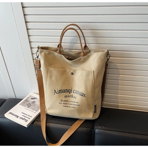 Detail of canvas tote bag with brown leather handles and adjustable shoulder strap