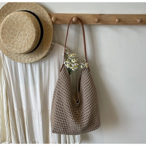 Detail of hollow woven tote bag with brown leather strap for summer beach vacation style