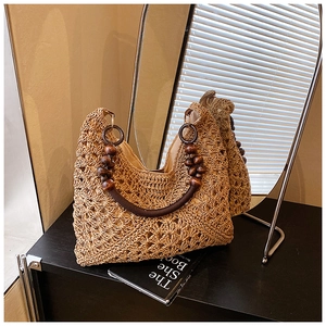 Macro shot of hand-woven straw tote bag with brown wooden bead handles on a black surface