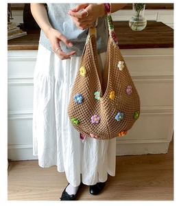 Close-up of khaki crochet beach bag featuring colorful 3D knit flowers and woven strap