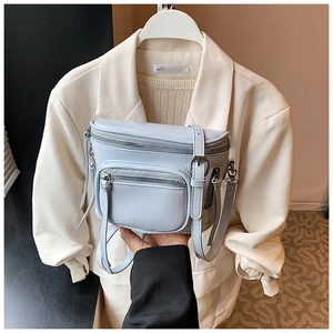 Détail du sac seau bleu clair montrant les poches zippées et la texture en cuir souple