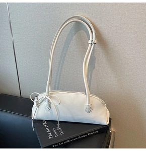Detail view of a white minimalist baguette bag with delicate bow knot on side