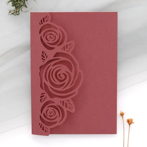 Detail of laser-cut burgundy rose patterns on high-quality paper wedding invitation card