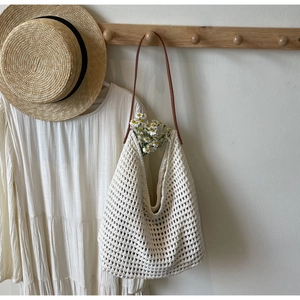 Detailed macro of creamy hollow crochet knit tote bag with brown leather shoulder strap